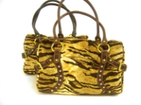 Tiger Pattern Faux Fur fashion handbag has a studded trim in the front, a double handle and a top zipper closure. Belt accents on the sides of the bag. 