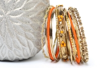 This 15 pieces set of fashion bangles includes one wide patterned bangle with orange beads on it, 2 orange bangles have fabric on it, 2 have metal pattern on it & rest have glitter. 