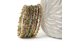 Gold colored Metal Fashion Bangles Set with Beads in Shades of Green. Bangles have a wavy pattern which is embellished with beads all around it. Sized to fit small to medium wrists.