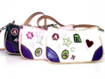 PVC Fashion Handbag has a single strap, a top zipper closure and embellished letters and shapes. Made of faux leather.