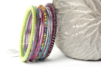 Colorful & lightweight 12 pieces bangles set can be matched with any kind of outfit. 9 thin glittery bangles, one thin beaded bangle & 2 threaded bangles - one lime green & one multi colored. Hand crafted in India.