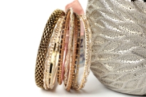 This set of fashionable bangles set includes 14 Pieces in different colors & patterns. Patterned gold colored metal wide bangle with 13 thin bangles which have glitter designs on them.